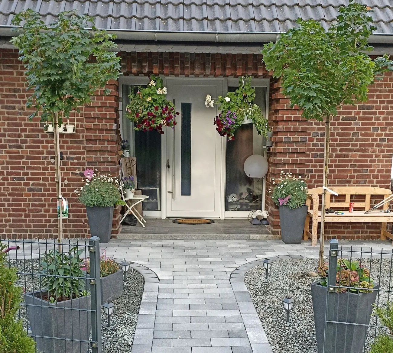 Gestalteter Eingangsbereich mit Pflasterweg und Bepflanzung